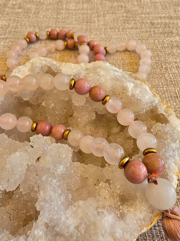 Gros plan sur les perles de quartz rose, les intercalaires dorés et les perles de rhodonite