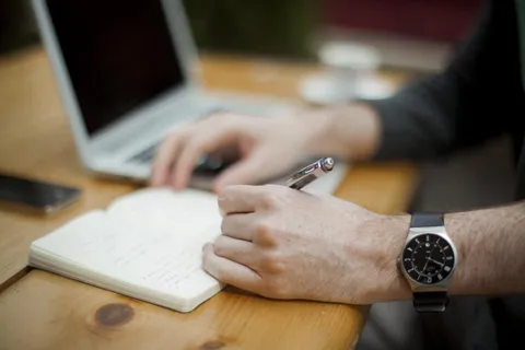 Mains qui prennent des notes dans un carnet sur une table en bois