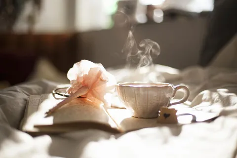 Tasse fumante posée sur un livre ouvert, dans une lumière douce
