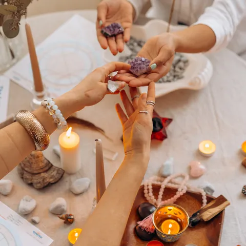Mains qui disposent des pierres et des cristaux sur une table, entre des bougies